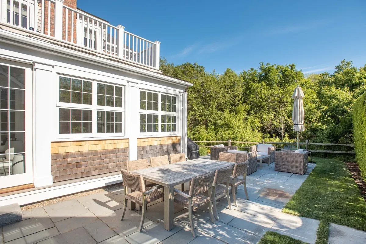Sunny bluestone patio with an outdoor dining table beneath the master balcony