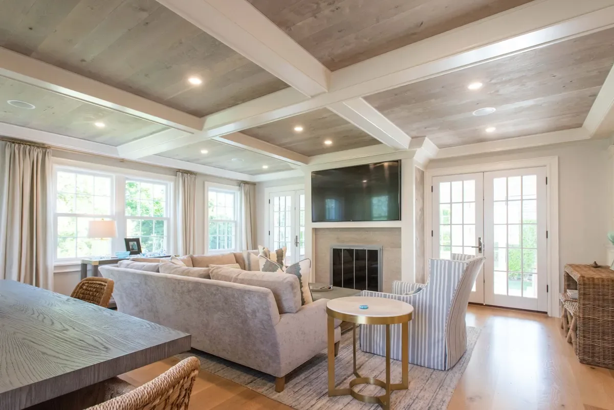 Living room with a sectional before the fireplace and French doors to the three-season porch on both sides