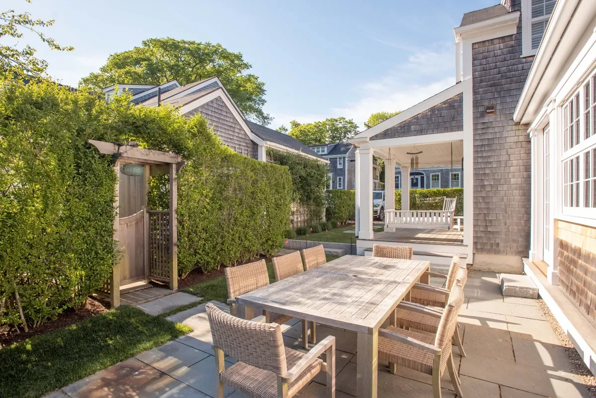 Teak dining table on the patio with the covered side porch beyond
