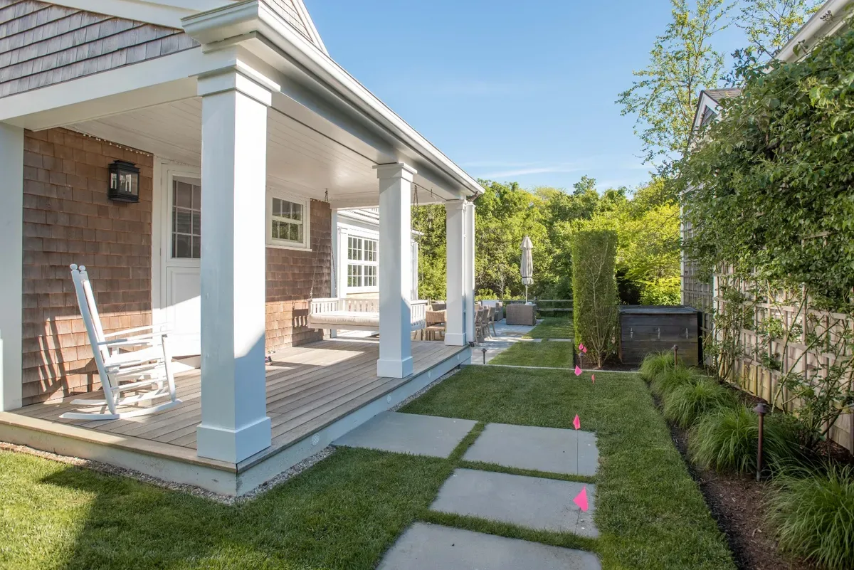 Covered side porch with white columns and a bluestone path across the lawn