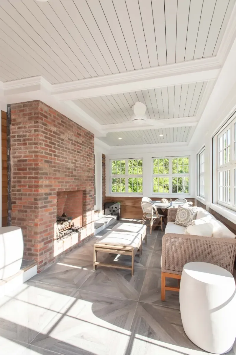 Three-season porch with its fireplace and a wall of windows onto the garden